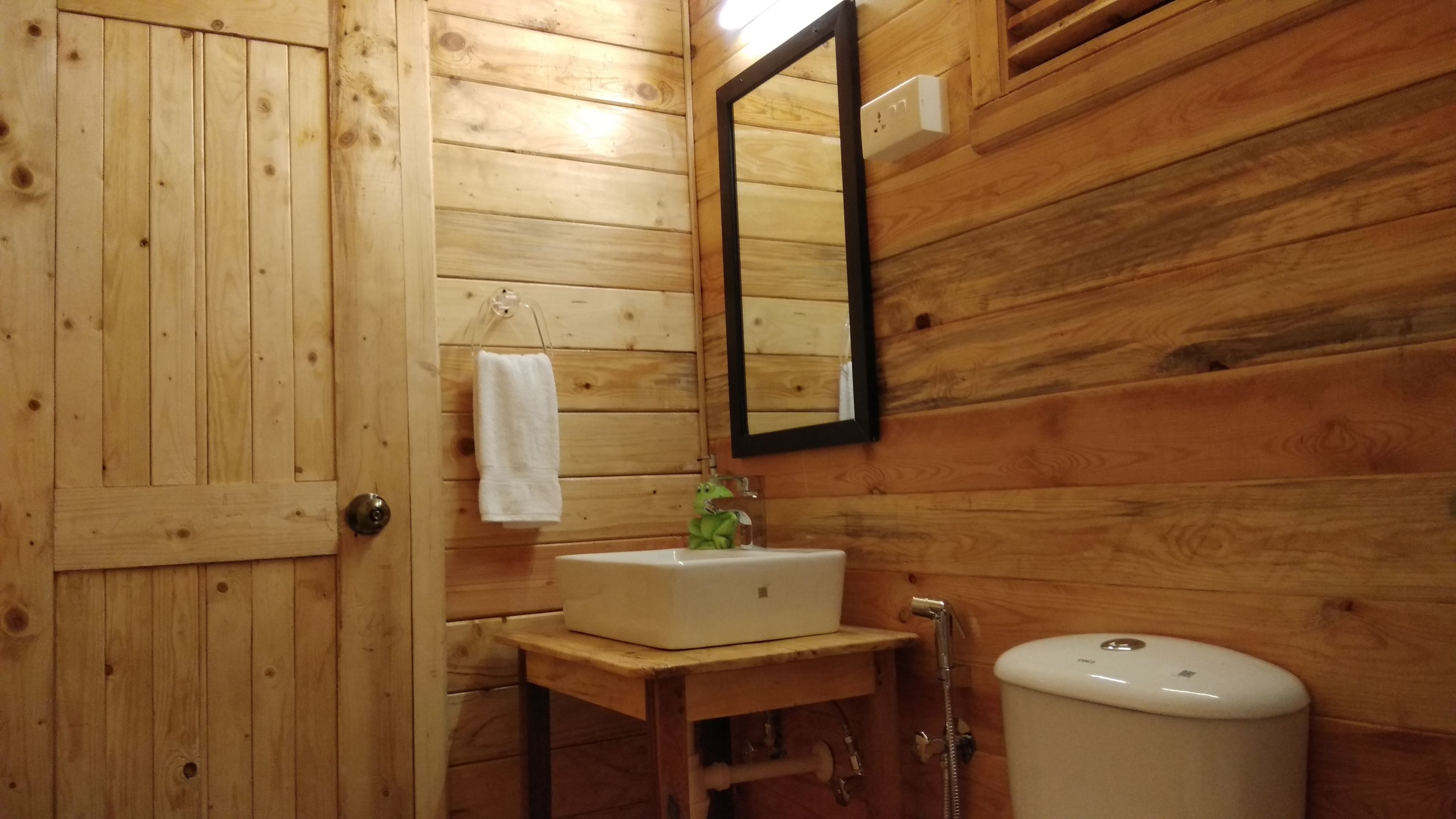 Un baño de madera con lavabo, espejo y retrete.