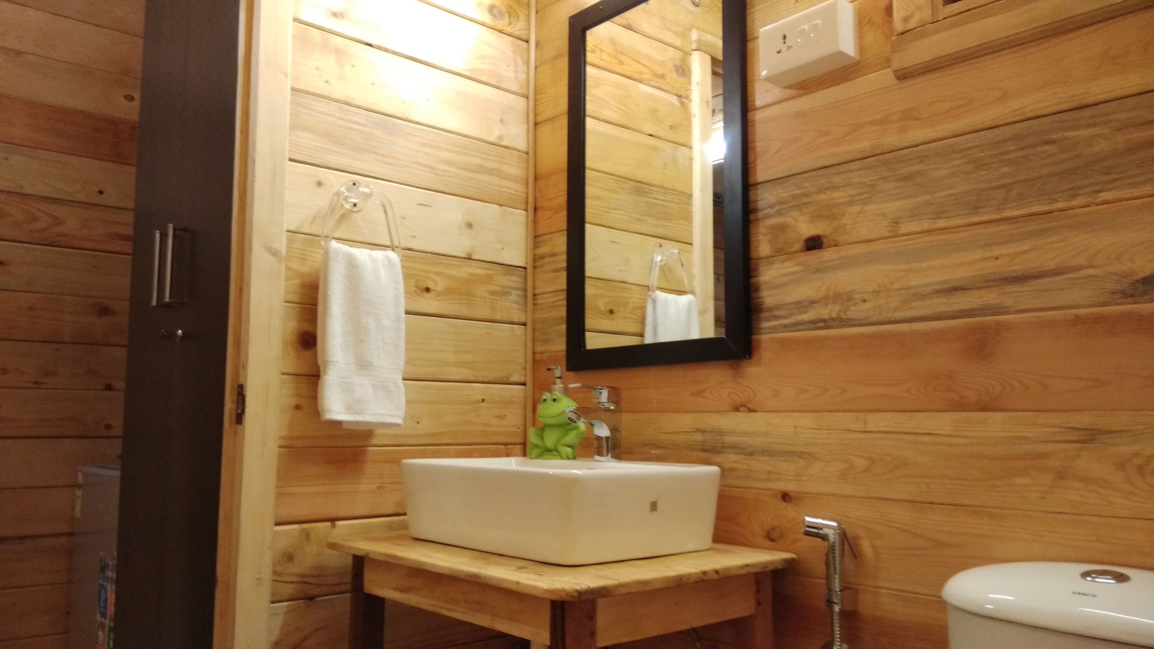 A wooden cabin bathroom with a white sink, a mirror, and a toilet.