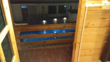 Interior de madera con un elemento acuático de azulejos azules, suelo de madera y pared con estampado.