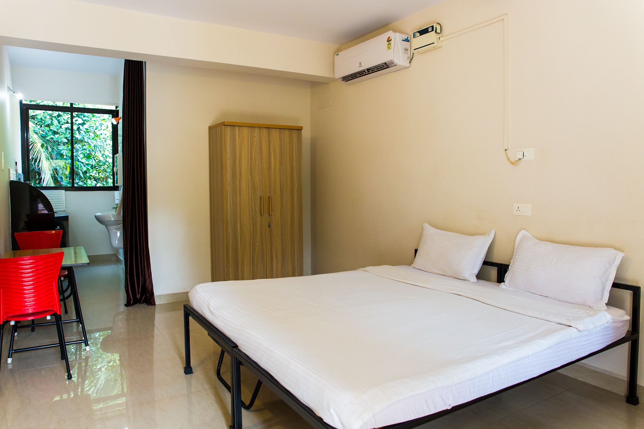 A hotel room with a bed, a desk, a chair, and a wardrobe.