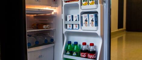 An open refrigerator with shelves containing beverages, including Sprite, Coca-Cola, and Minute Maid juice cartons.