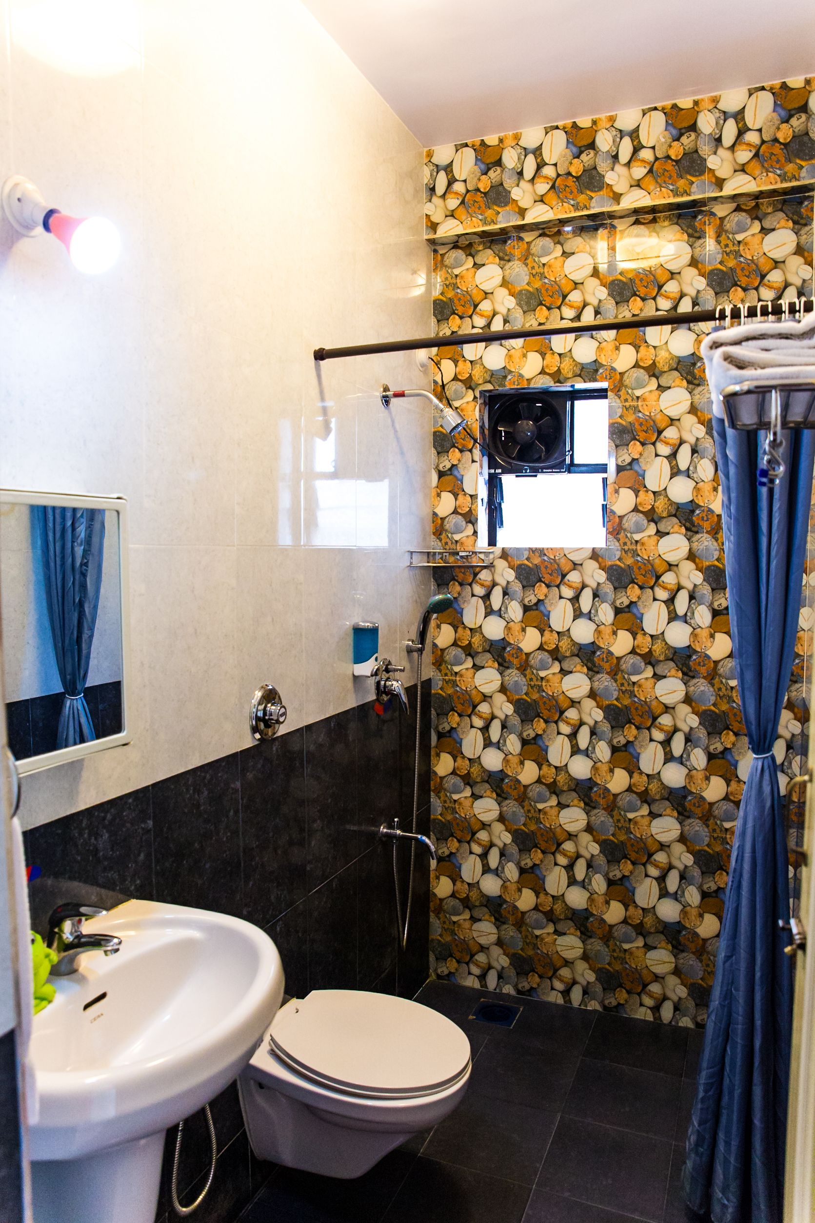 A bathroom with a stone wall, a white sink, a toilet, and a shower with a glass door.