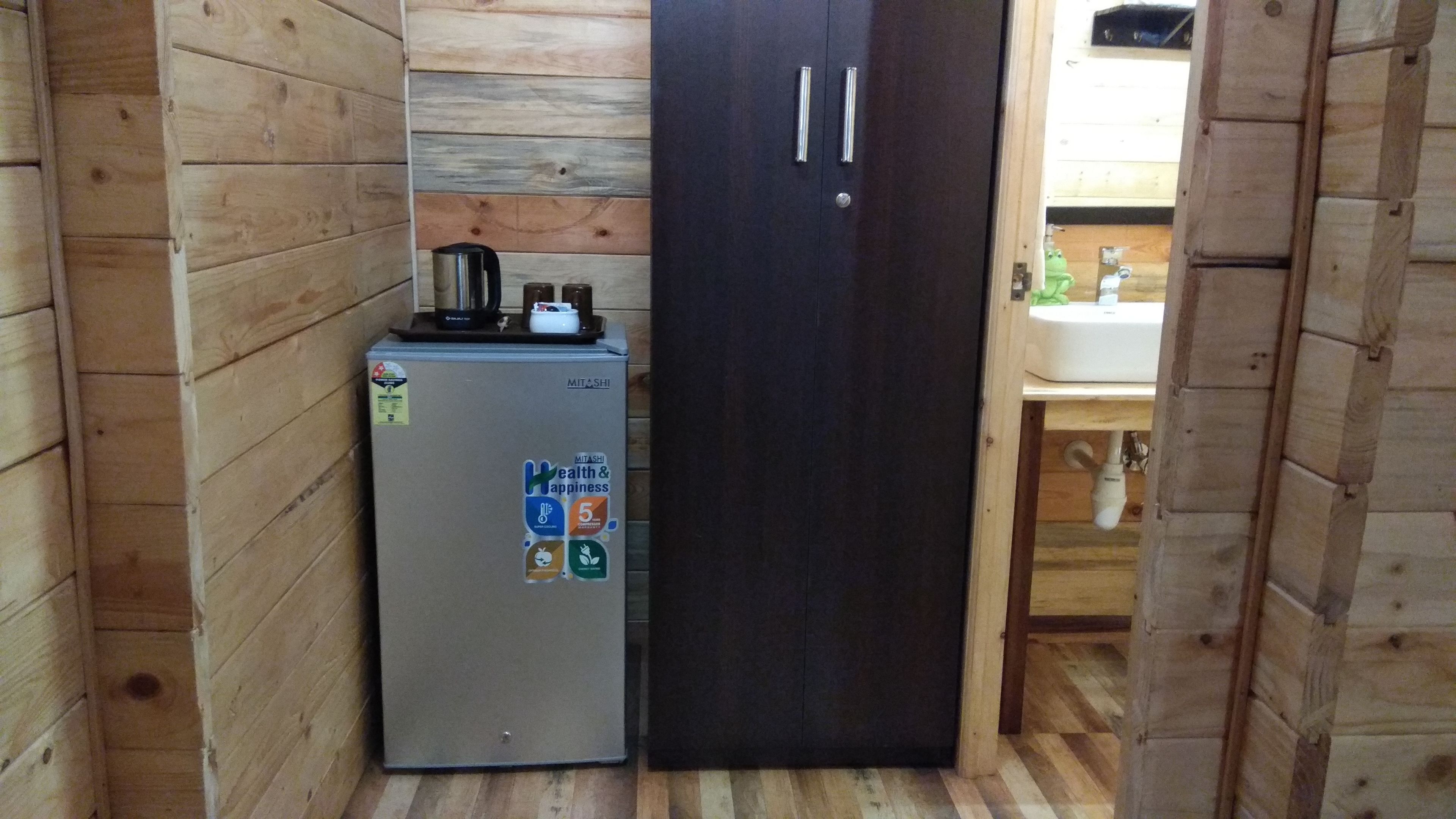 A compact kitchen with a refrigerator, a coffee maker, and a sink.
