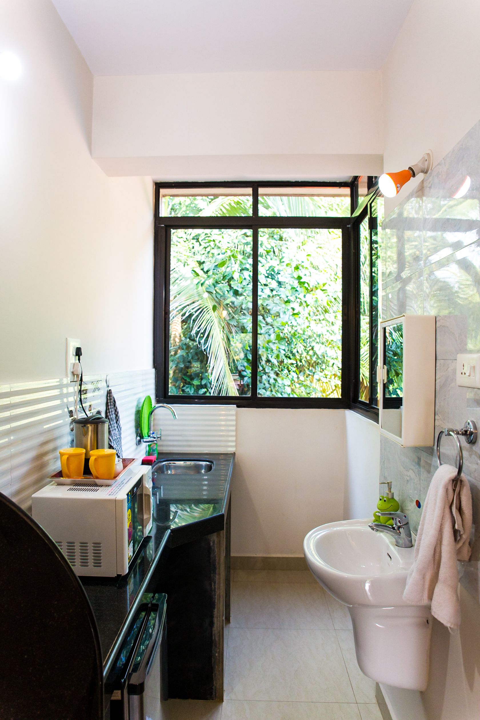 A modern bathroom with a black countertop, a white sink, and a window with a view of greenery.