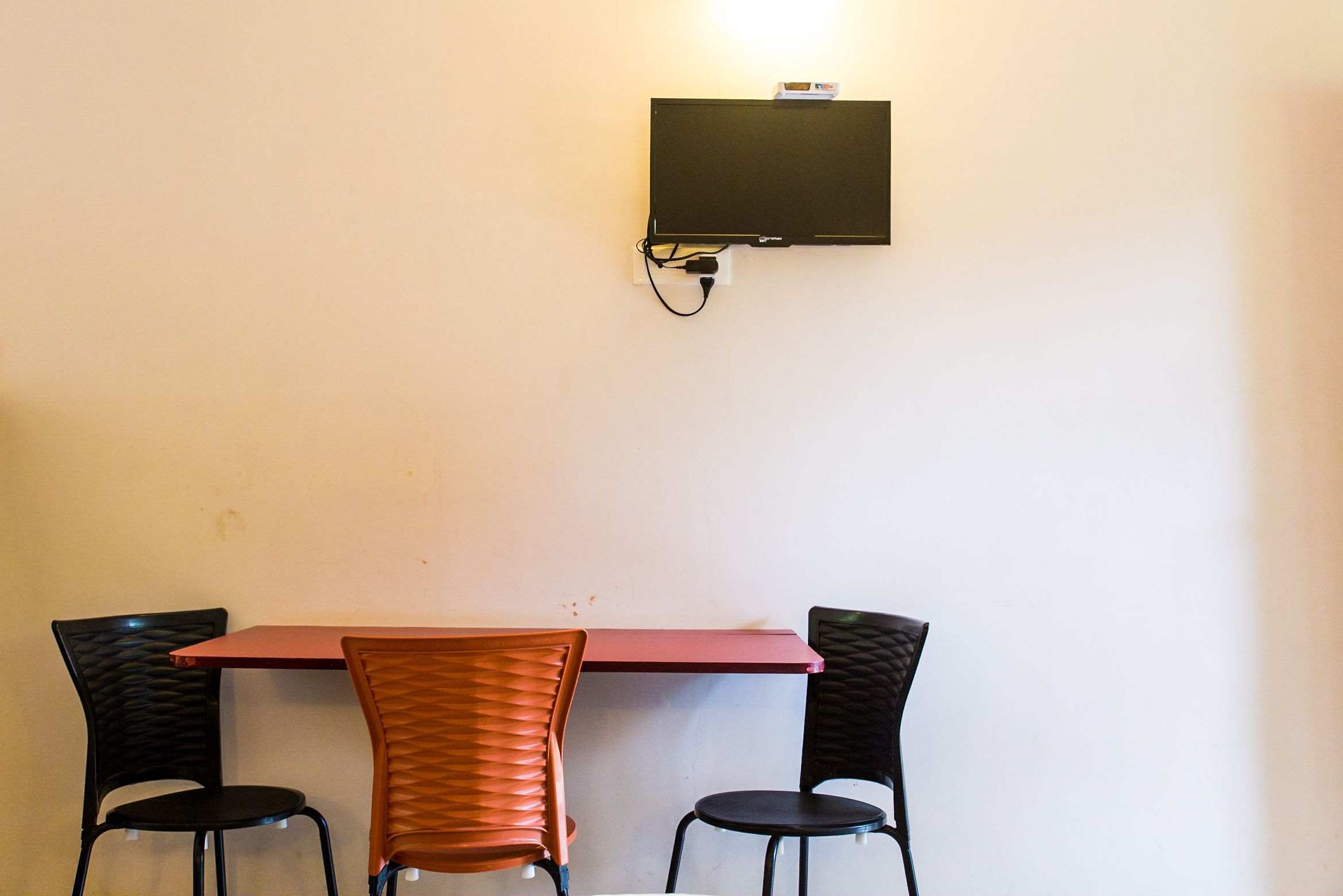 Een vergadertafel met twee stoelen, een wandgemonteerde flatscreen televisie en een stopcontact.