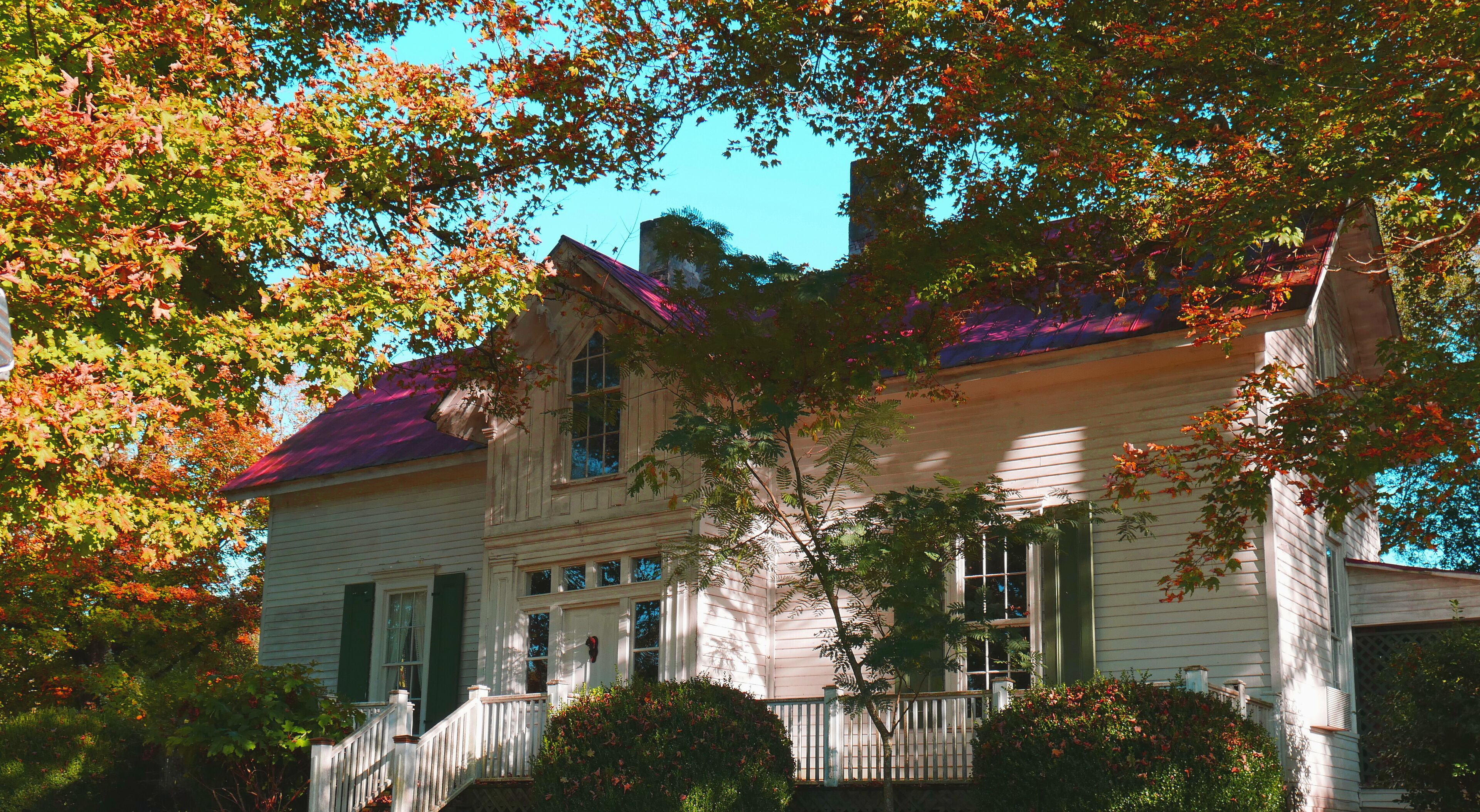 A two-story house with a red roof, green shutters, and a white exterior.