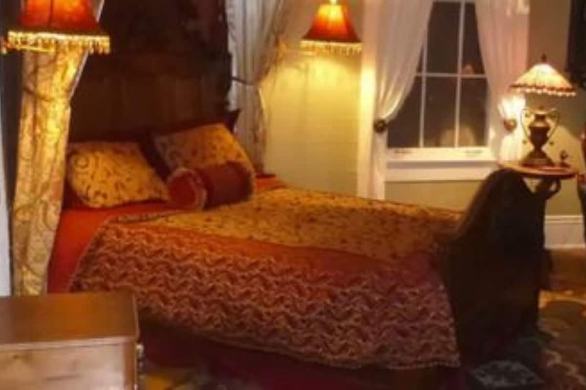 A bedroom with a bed, a chair, a lamp, and a window.