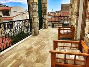 A balcony with a stone wall, a metal railing, and a view of red-tiled rooftops. - Parmis Boutique House (Cesme)