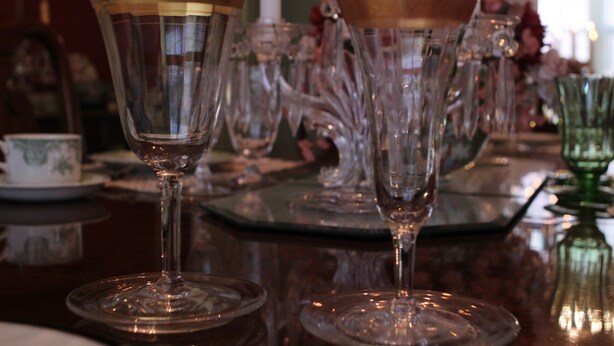 A table with several clear glass wine glasses and a green glass bottle. - Moore House Bed and Breakfast (Manhattan)