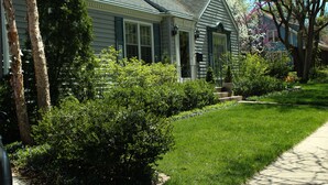 A house with a well-maintained lawn, a pathway leading to the front door, and a small garden area with various plants. - Moore House Bed and Breakfast (Manhattan)