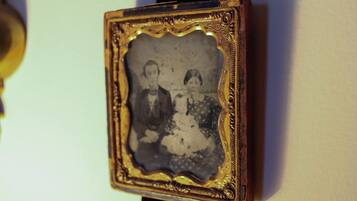 A vintage photograph with ornate gold frame, mounted on a wall.