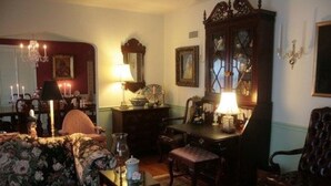 A traditional room with a floral sofa, a wooden cabinet, and a chandelier. - Moore House Bed and Breakfast (Manhattan)