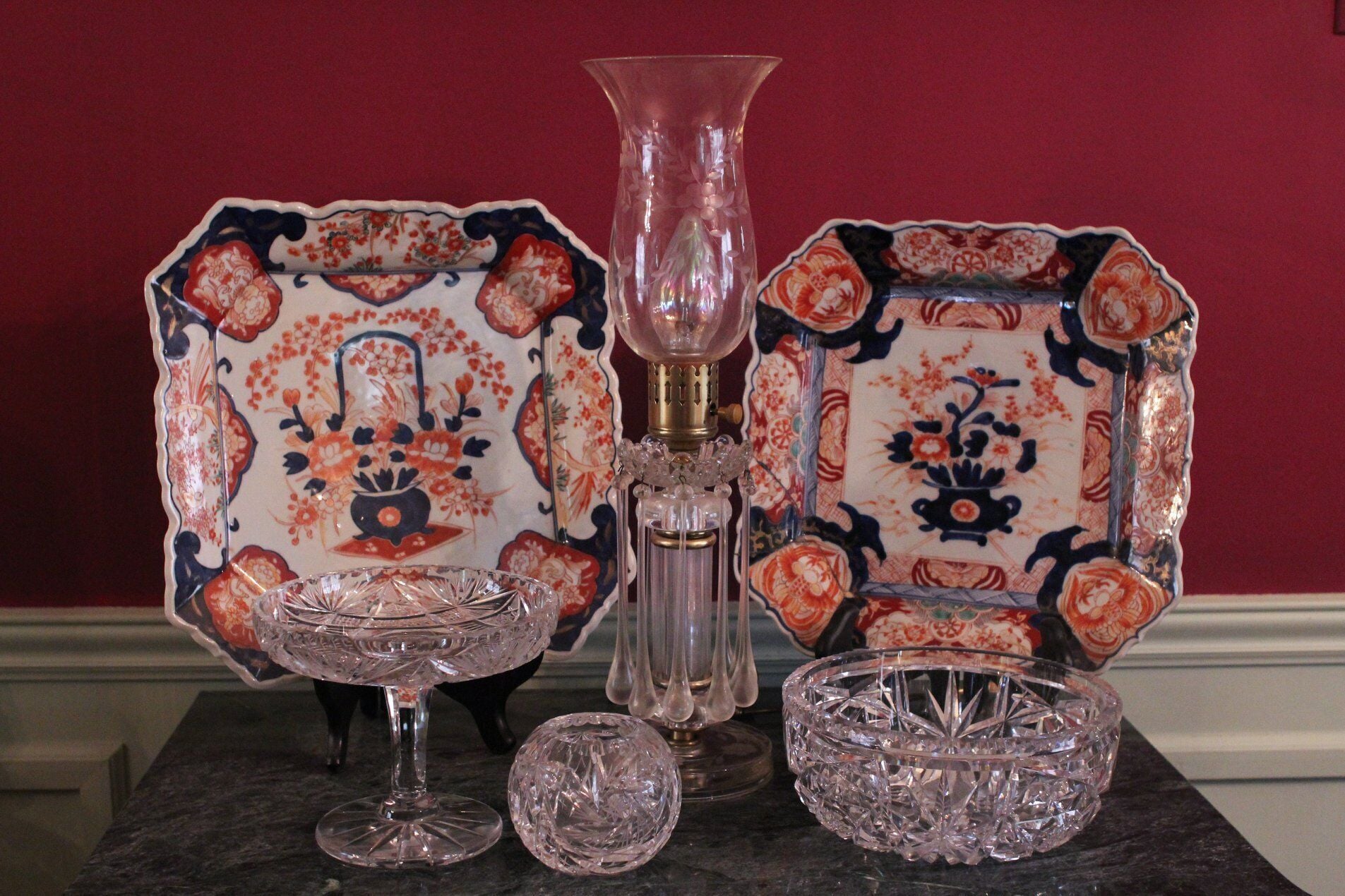 A table with a decorative plate, a glass vase, and a crystal glass set.