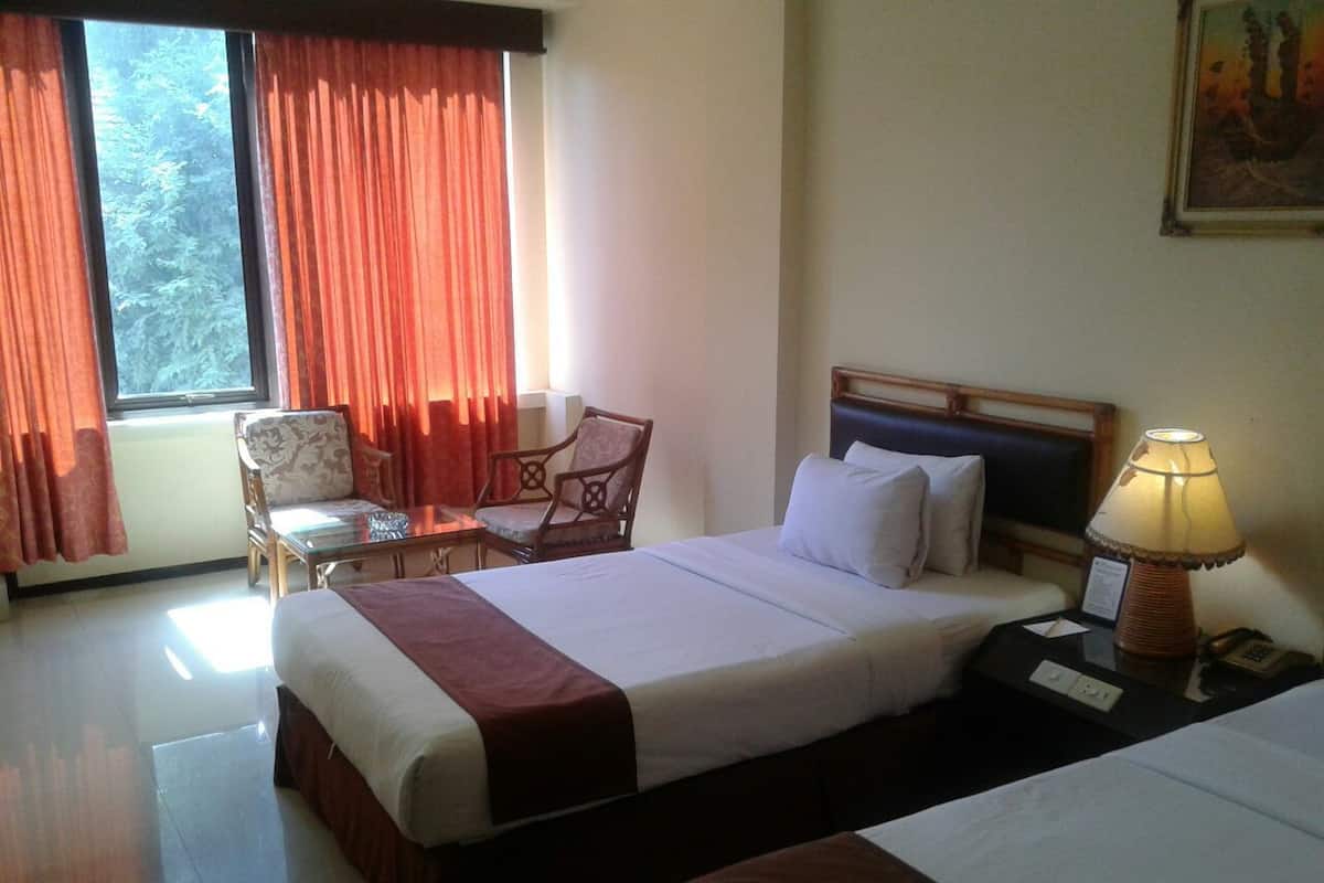 Habitación de hotel con cama, una silla, un escritorio y una lámpara.
