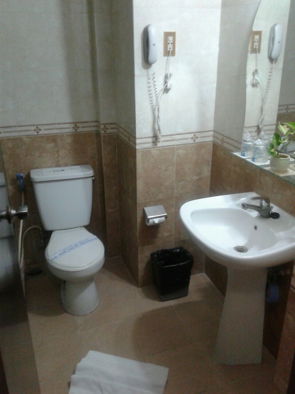 Une salle de bain équipée de toilettes, d’un lavabo et d’un téléphone.