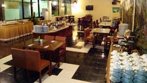 Un restaurante con techo alto, una zona de bar y varias mesas y sillas para comer.