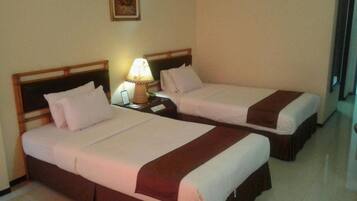 A hotel room with two beds, a nightstand with a lamp, and a painting on the wall.