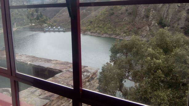 A view of a river with a bridge and hills in the background.
