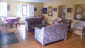 A living room with a sofa, armchairs, a dining table, and chairs.