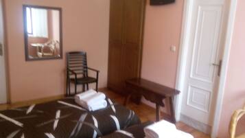 A bedroom with a bed, a chair, a table, and a door.
