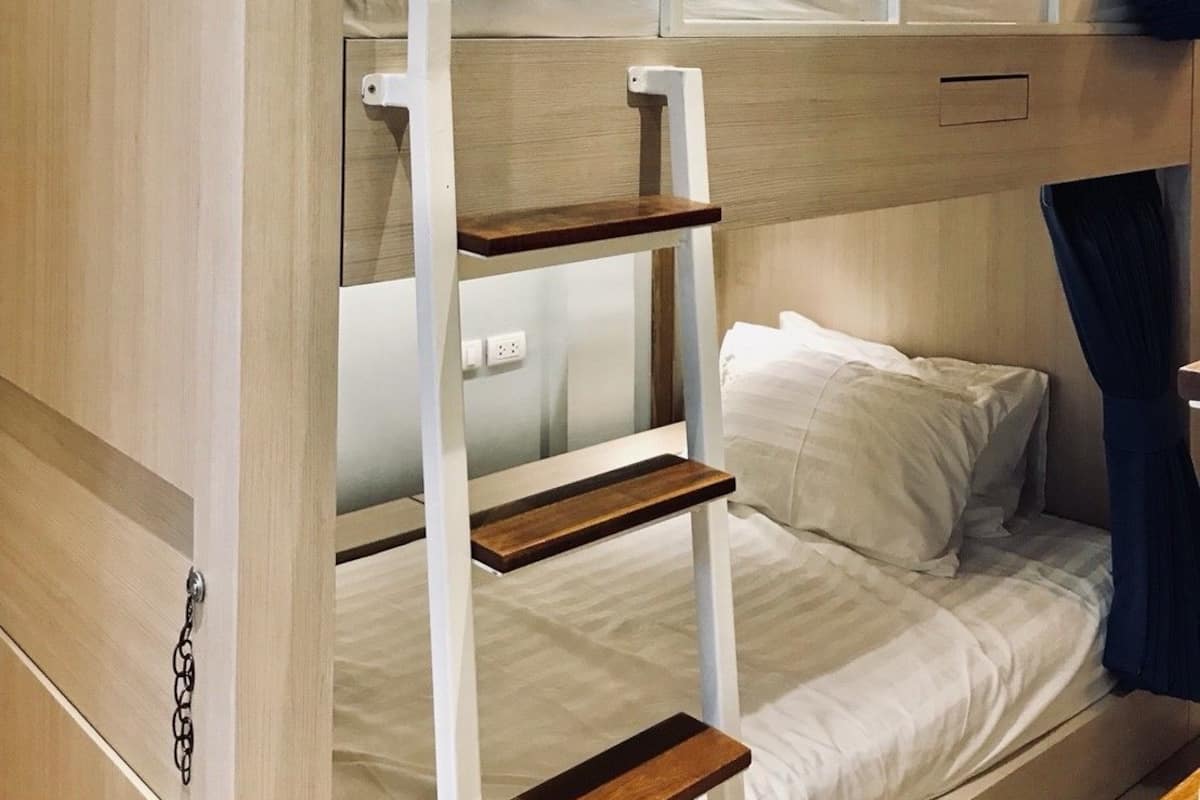 A bunk bed room with a wooden finish, a ladder, and a small shelf.