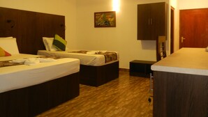 A hotel room with two beds, a wooden floor, a painting on the wall, and a small cabinet. - Eeescart Family Resort (Bandarawela)