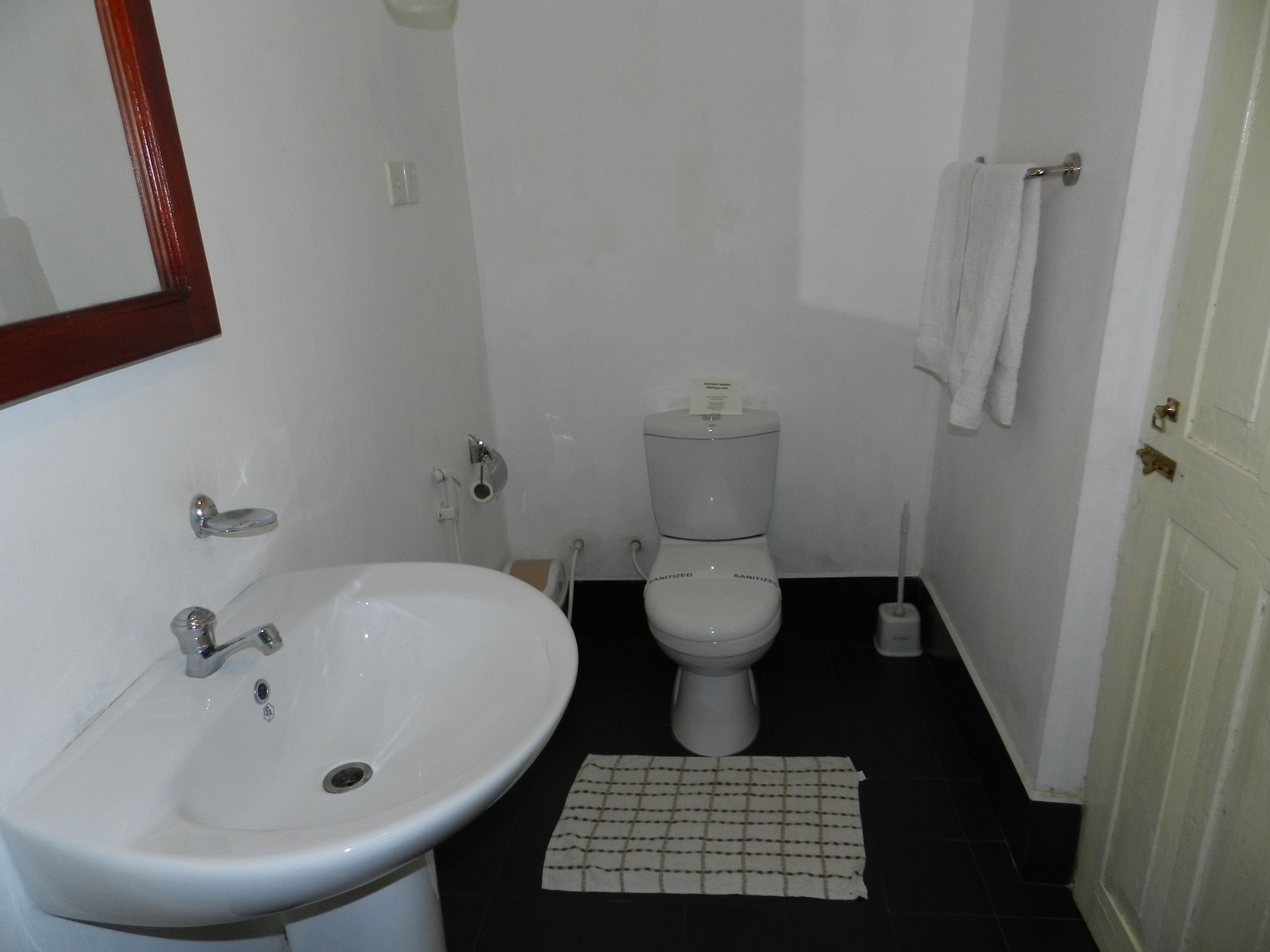 A small bathroom with a white sink, toilet, and a mirror.