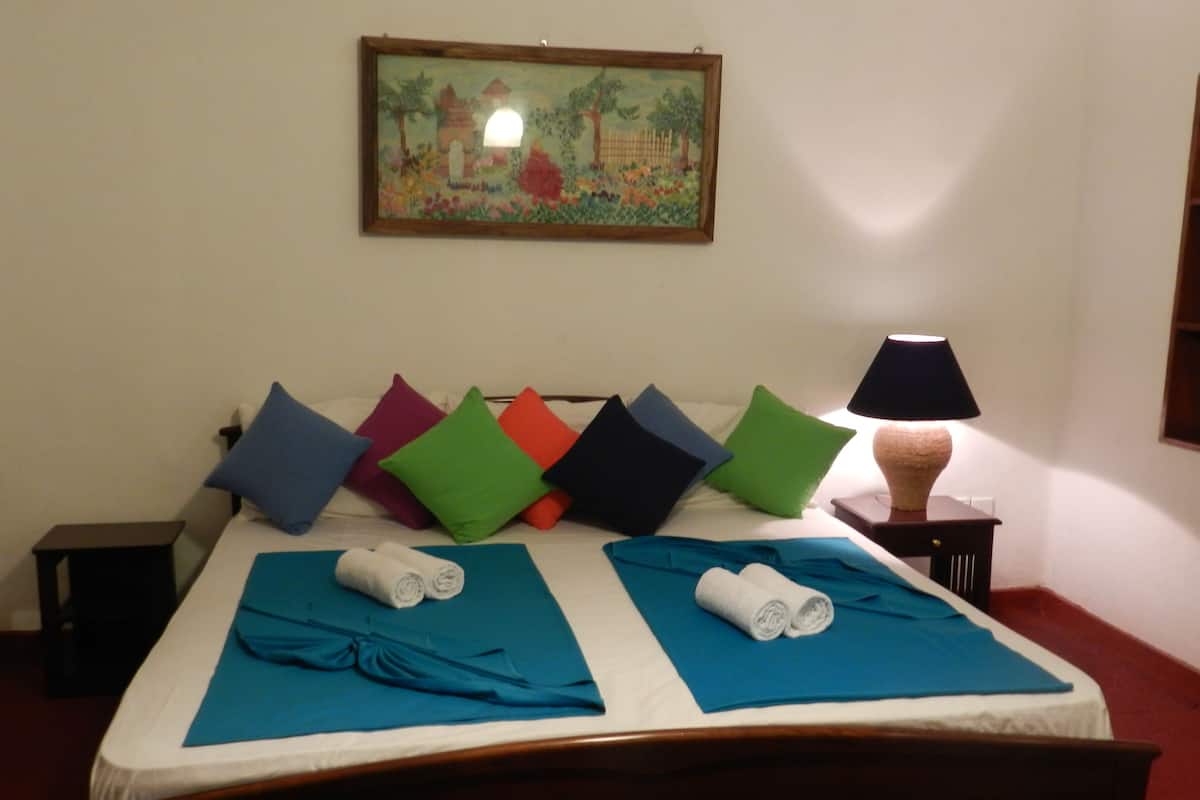 Una habitación de hotel con una cama, almohadas, una lámpara y un cuadro en la pared.