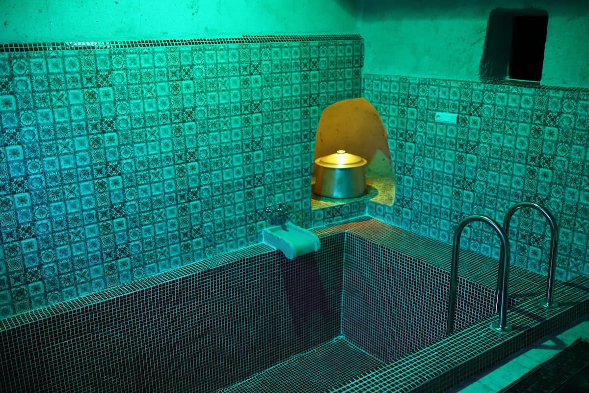 Un baño con pared de azulejos, un lavamanos y un perchero para toallas.