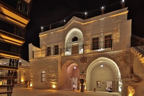 A historic building with a stone facade, arched entrances, and a balcony with railings. - Fosil Cave Hotel (Ürgüp)