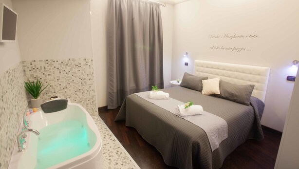 Una habitación de hotel moderna con una cama grande, una bañera y una mesita de noche pequeña.