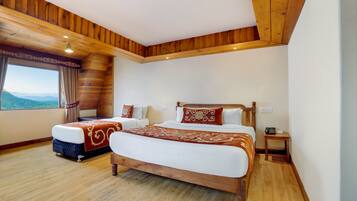 A bedroom with two beds, wooden ceiling, large window with curtains, and a view of the mountains.