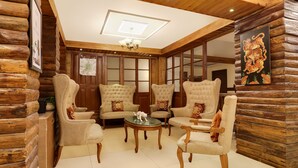 A cozy room with wooden log walls, a chandelier, and plush armchairs around a central table. - Summit Hermon Hotel & Spa (Darjeeling)