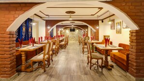 A restaurant with brick walls, wooden tables, and chairs arranged in a long dining area. - Summit Hermon Hotel & Spa (Darjeeling)
