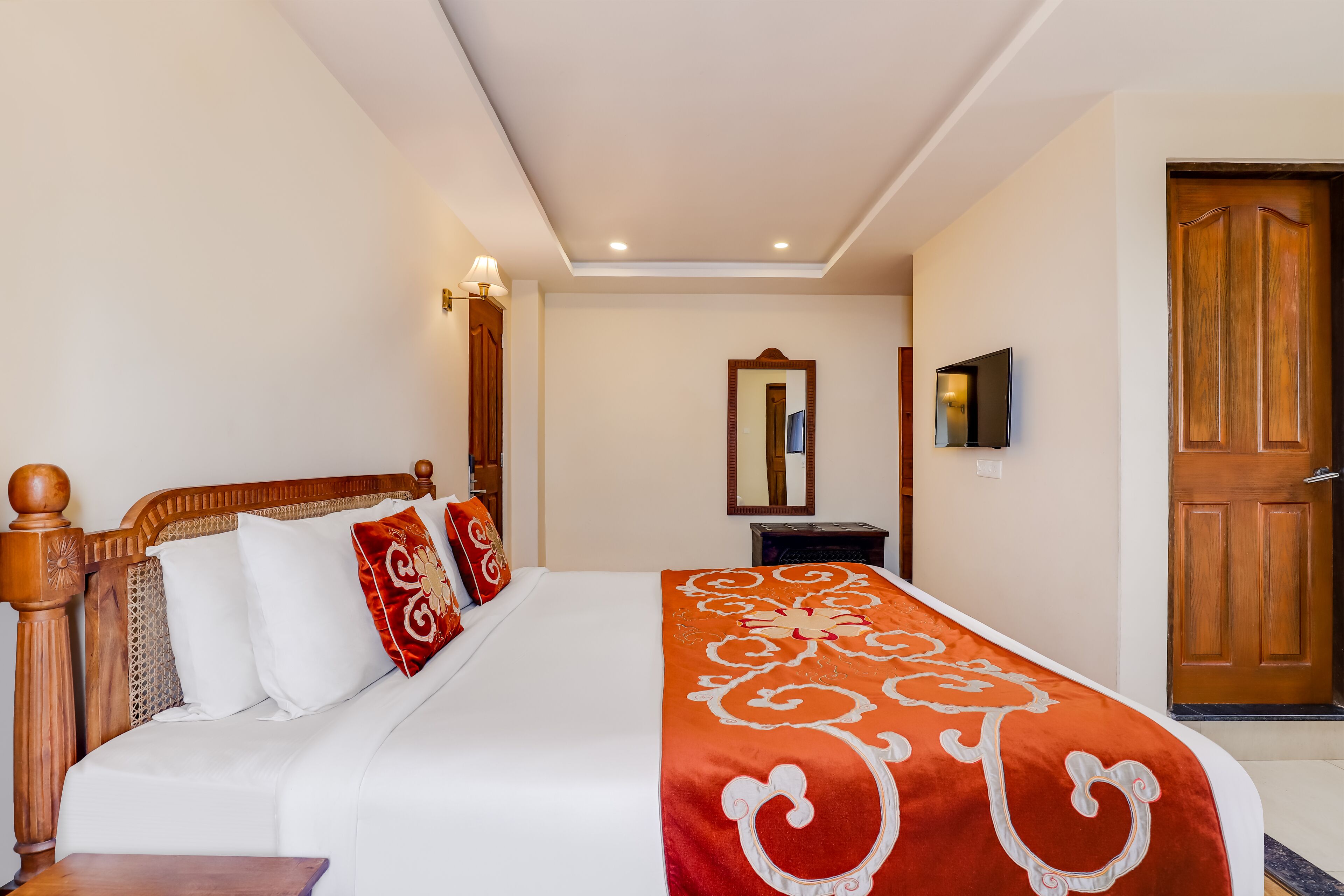 A neatly made bed with a red and white blanket, a wooden headboard, and a small bedside table.
