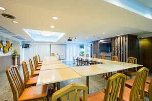 A conference room with a long table and chairs, a projector, and a television on the wall. - Samran Place Hotel (Bangkok)