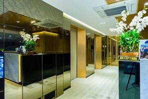 A reception area with a reception desk, a potted plant, and a sign labeled "RECEPTION". - Samran Place Hotel (Bangkok)