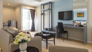 Ein modernes Hotelzimmer mit einer Couch, einem Esstisch, einem Fernseher und einem Schreibtisch.