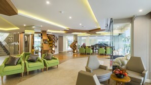 Eine geräumige Lobby mit grünen und beigen Sitzgelegenheiten, einer Treppe und einem modernen Deckenstil.