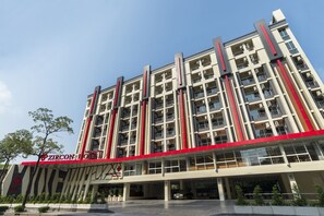 Un hotel de varios pisos con un diseño arquitectónico moderno, con balcones y una entrada destacada.