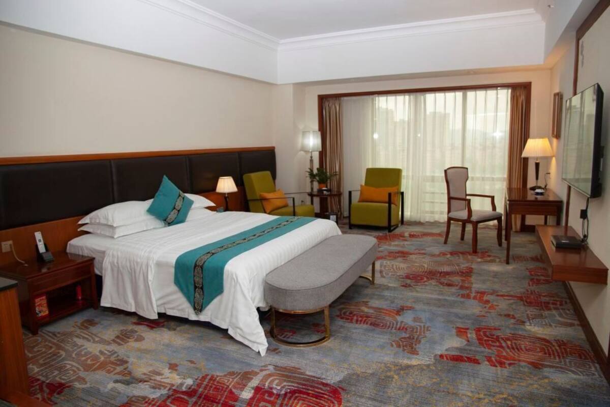 A hotel room with a large bed, a desk, a chair, and a television.