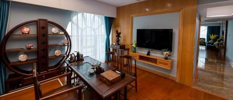 Una sala de estar moderna con una mesa de comedor de madera, sillas, un televisor y un estante decorativo.