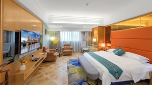 Ein Hotelzimmer mit einem großen Bett, einem Schreibtisch mit Flachbildfernseher, einer Couch und einem Sessel.
