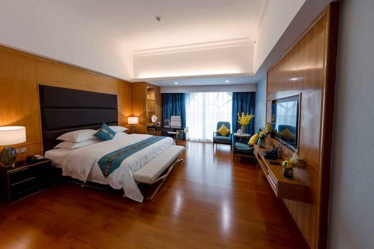 A modern hotel room with a large bed, a desk, and a seating area.