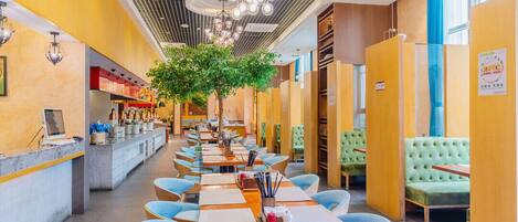 A restaurant with long communal tables, individual booths, and a central tree.