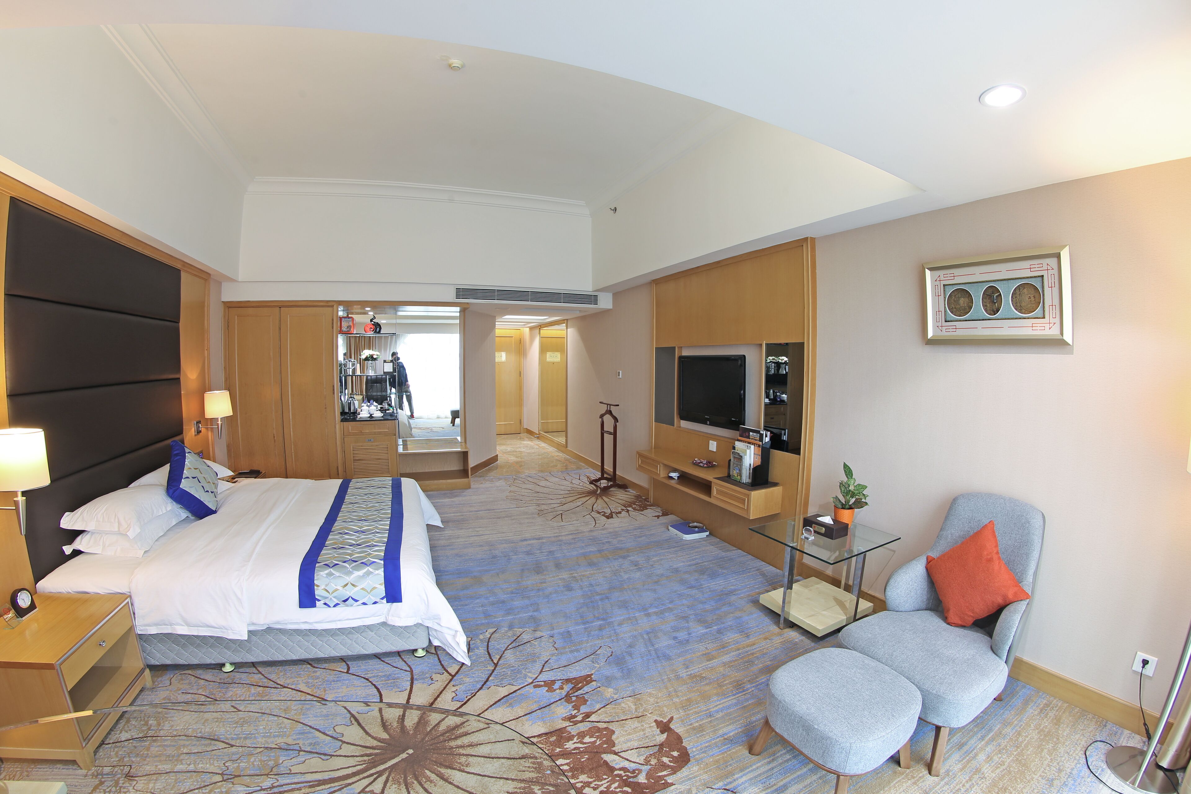 A hotel room with a large bed, a TV, a chair, and a desk.