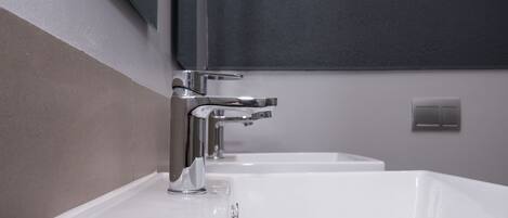 Uma casa de banho moderna com torneira de aço e lavatório branco.