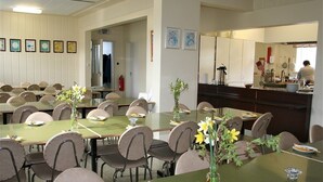 A dining area with multiple tables and chairs, a kitchen area visible through an open doorway, and framed pictures on the wall. - Húsabakki Guesthouse (Dalvik)