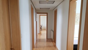 A hallway with wooden doors and a wooden floor, leading to a dining area with a table and chairs. - Húsabakki Guesthouse (Dalvik)