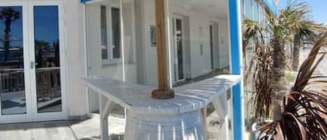 A beachside restaurant with a thatched umbrella, a clear view of the sea, and a wooden deck.